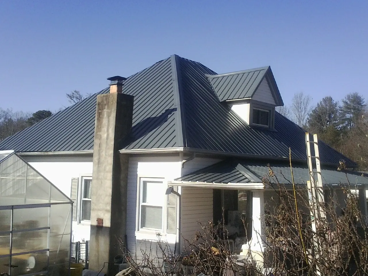 Dark blue standing seam metal roof on a white farmhouse with dormer — Slate & Tile Roof Repair by Roofing Brothers in Coshocton