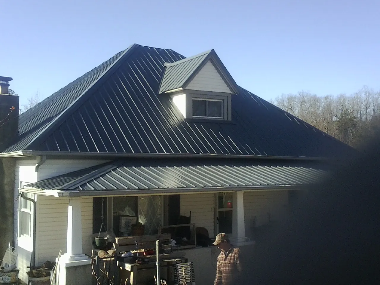 Dark blue standing seam metal roof with a dormer above a front porch in Coshocton