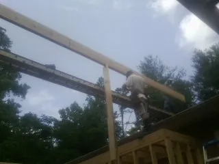 Carpenter setting a ridge beam over a new addition frame — Ice Dam Removal by Roofing Brothers in Coshocton