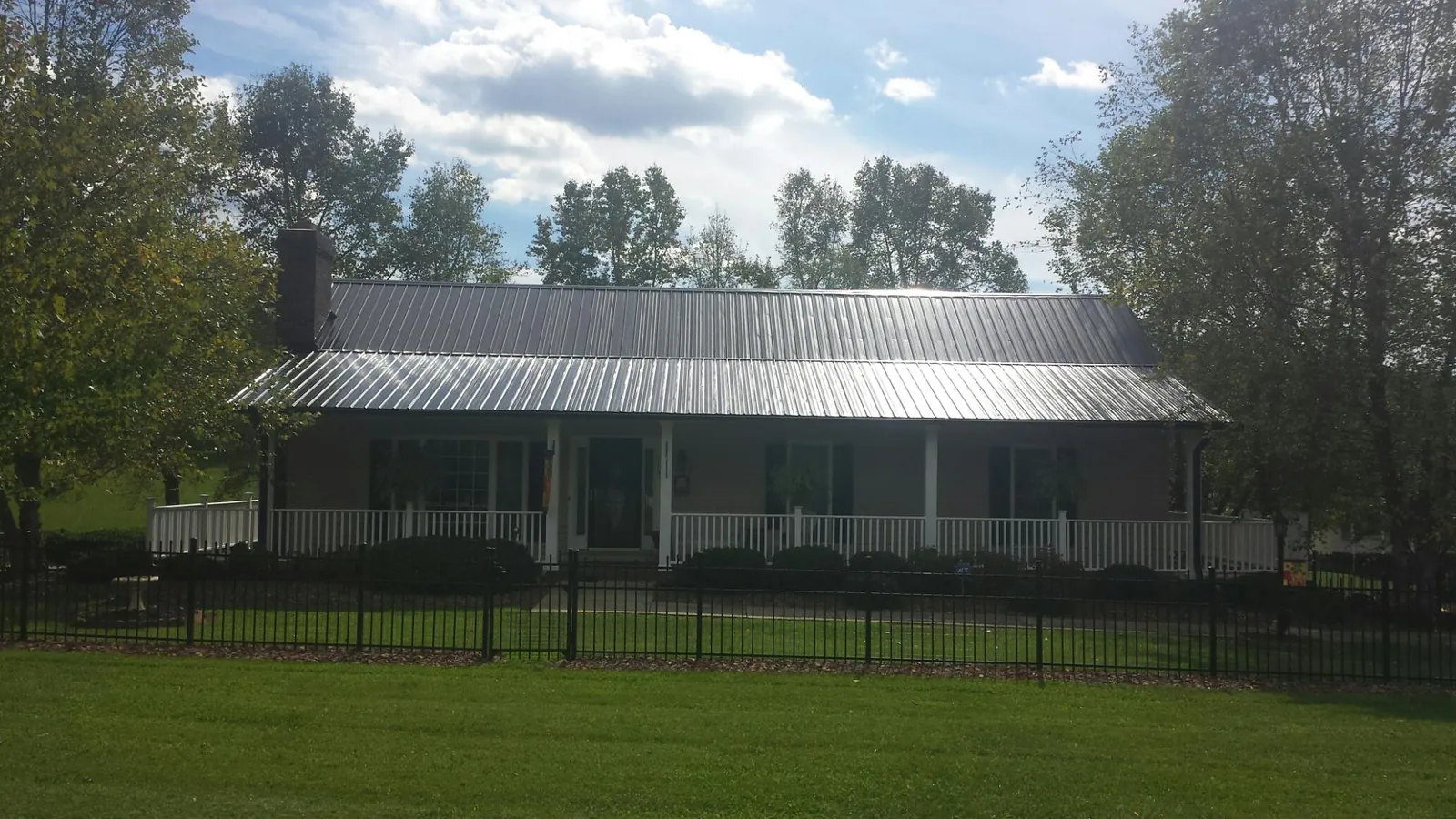 Gray metal roof on a brick ranch with a full width front porch — Gutter Guard Installation work by our crew in Coshocton