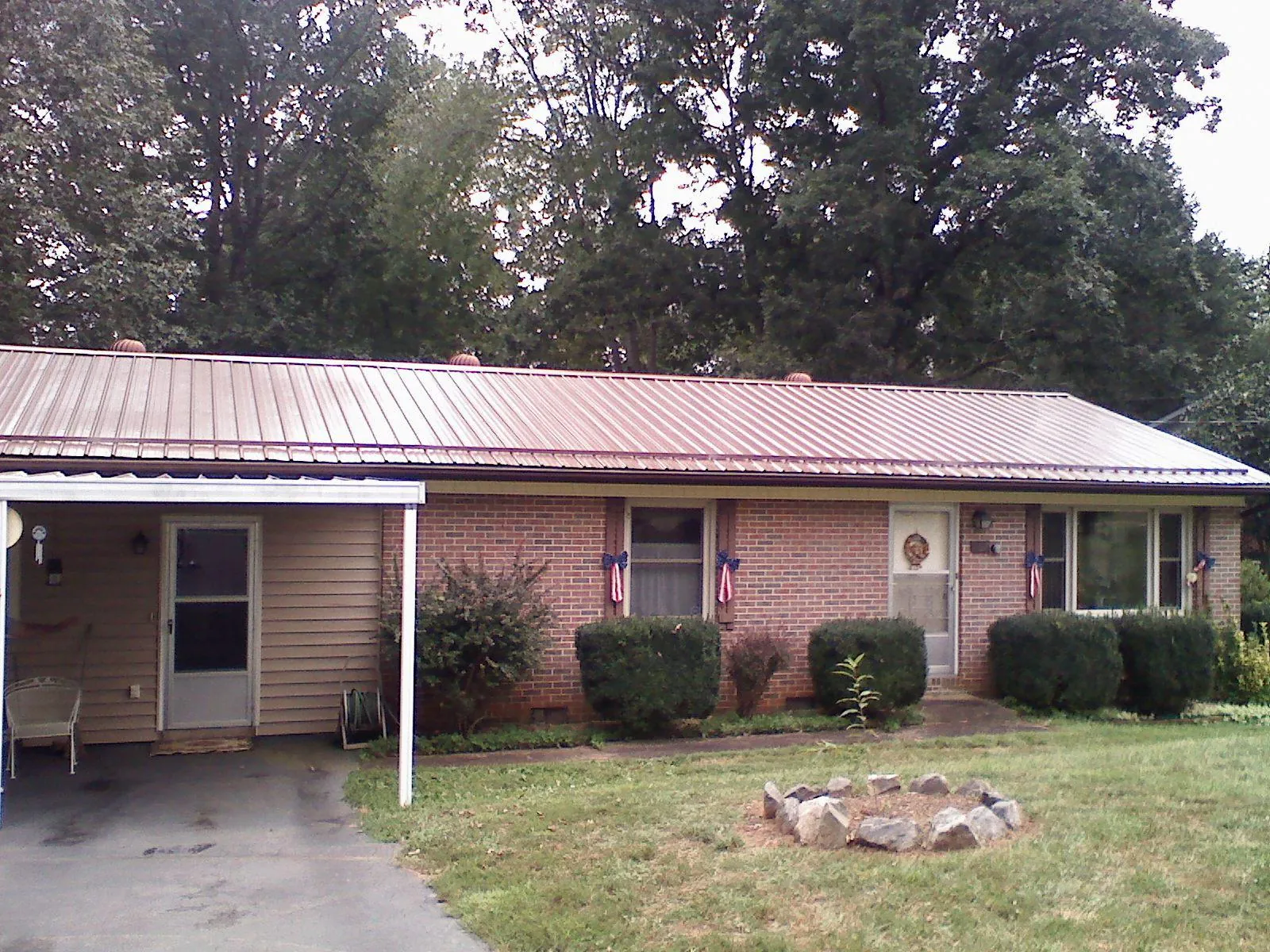 Bronze metal roof and carport on a brick ranch home — Roof Repair work by our crew in Coshocton